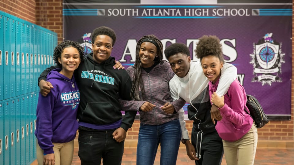 Students smiling in front of sign