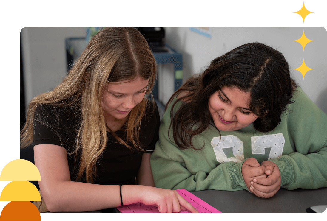 Two BARR students looking at an assignment and smiling